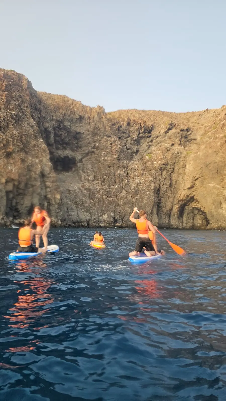 Grupo navegando en paddle surf frente a los acantilados